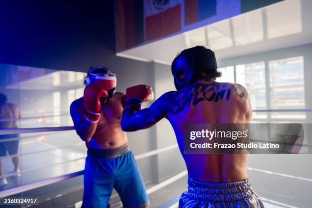 young man boxer fighting in a ring - wrestlers fighting stock pictures, royalty-free photos & images
