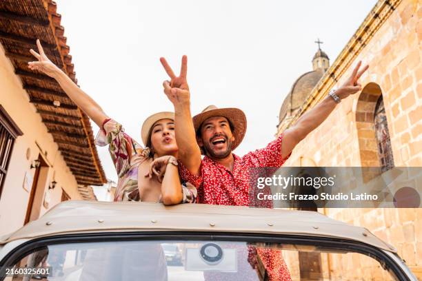 portrait of a tourist couple riding in a convertible car through the city streets - joy stock pictures, royalty-free photos & images