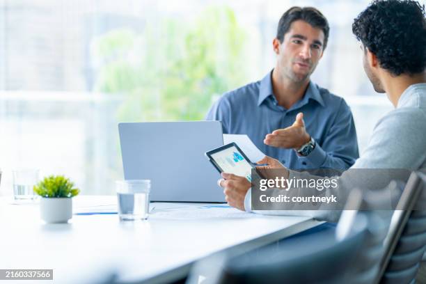 two businessmen working on a digital tablet and laptop computer in the office. - tax stock pictures, royalty-free photos & images