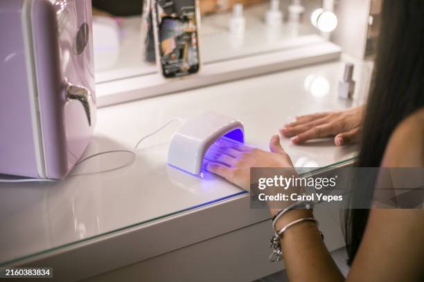 woman drying nails under uv lamp during manicure. - manicure stock pictures, royalty-free photos & images