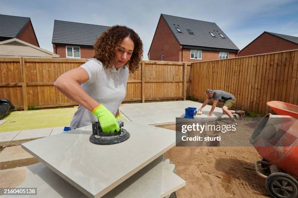female landscaper laying porcelain patio tiles - landscaped stock pictures, royalty-free photos & images