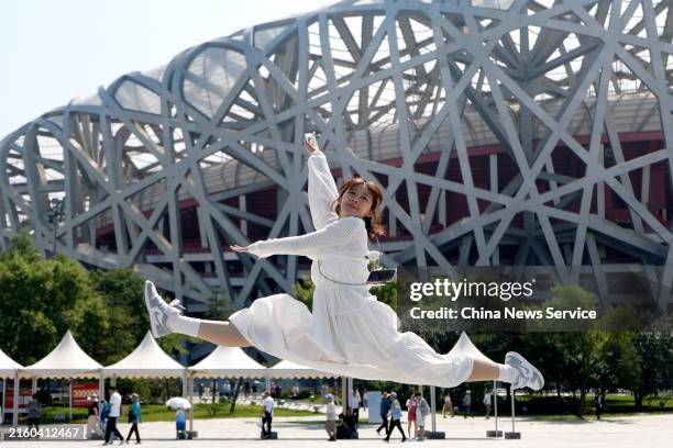 Girl from China's Taiwan region poses for a photo in front of the Beijing National Stadium during a journey of Cross-Strait Youth Exchange Camp on...