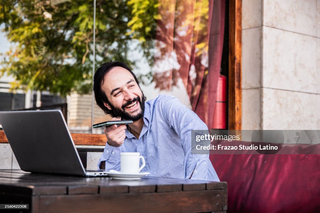Businessman sending a voicemail on sidewalk cafe