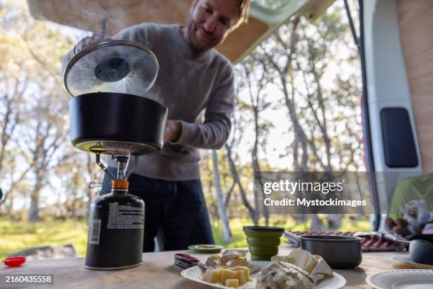 man cooking breakfast in camper van with prepared food - fogão de acampamento imagens e fotografias de stock