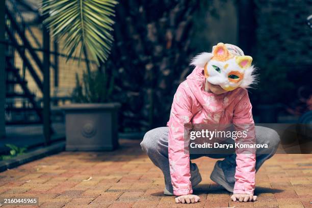 quadrobics. a girl in a cat mask is squatting outdoors. - maschere di carnevale foto e immagini stock