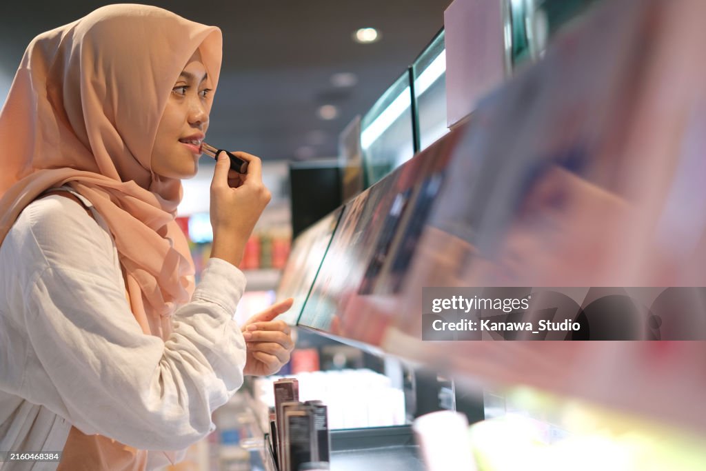 Femme musulmane indonésienne essayant du rouge à lèvres