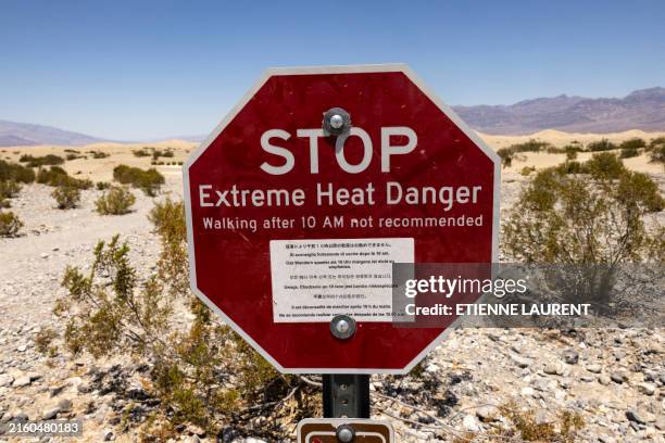 Sign reads "Stop Extreme Heat Danger" at Mesquite Flat Sand Dunes in Death Valley National Park near Furnace Creek during a heatwave impacting...