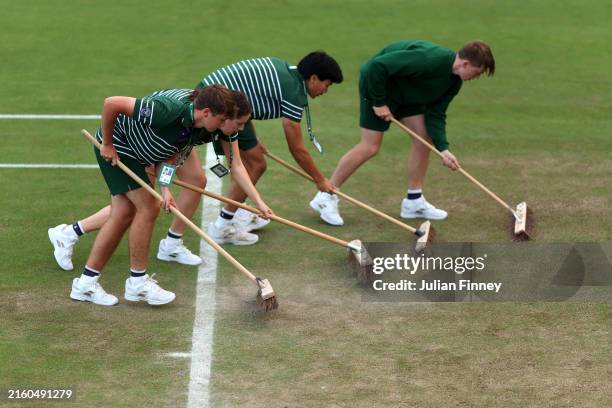 Members of the ground staff brush the court during day three of The Championships Wimbledon 2024 at All England Lawn Tennis and Croquet Club on July...