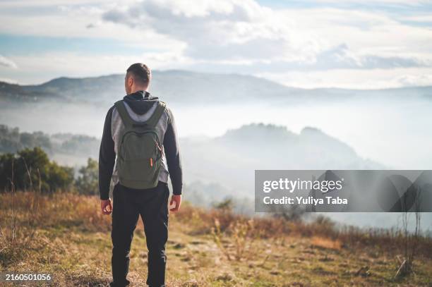 hiker looking at view in morning. - hill range stock pictures, royalty-free photos & images