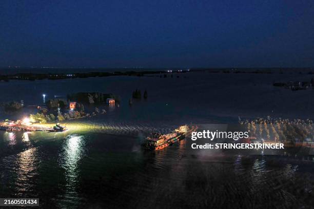 This photo taken on July 7, 2024 shows an aerial view of workers repairing a breach on an embankment of Dongting lake in Huarong county, in China's...