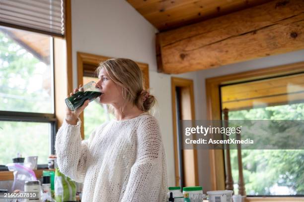 young woman drinks a healthy smoothie - green drink stock pictures, royalty-free photos & images
