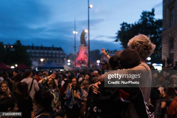 People are celebrating during an election night rally following the first results of the second round of France's legislative election at Republique...