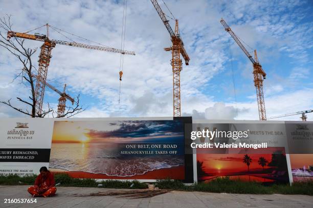 Woman sits near a billboard advertising China's Belt and Road Initiative on July 1 in Sihanoukville, Cambodia. China's property sector is grappling...