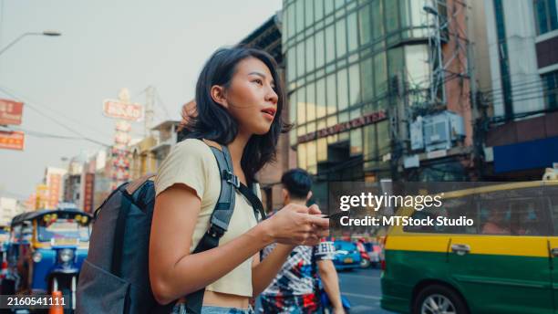 young asian woman backpacker using a mobile phone on the street in urban city. holiday vacation trip. - search for missing person stock pictures, royalty-free photos & images