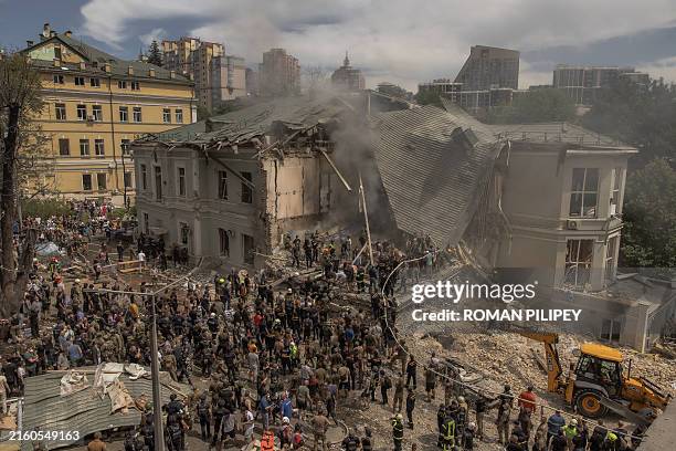 Emergency and rescue personnel along with medics and others clear the rubble of the destroyed building of Ohmatdyt Children's Hospital following a...
