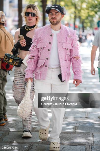 Guest wears white top, pink tweed distressed jacket, white pants, white bag, cream Crocs mules, outside Doublet, during the Haute Menswear...