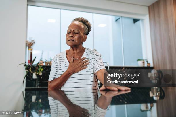 ältere frau, die zu hause schmerzen verspürt - reflux stock-fotos und bilder