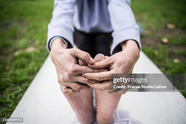 nahaufnahme einer frau, die zehen berührt, die im freien yoga praktiziert - zehenspitzen berühren stock-fotos und bilder