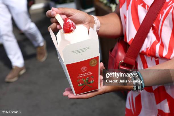 Spectator enjoys strawberries and cream during day four of The Championships Wimbledon 2024 at All England Lawn Tennis and Croquet Club on July 04,...