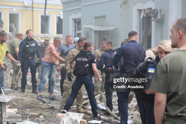 Emergency officials and civilians conduct search and rescue operations among the rubble of buildings destroyed by missile attack including...