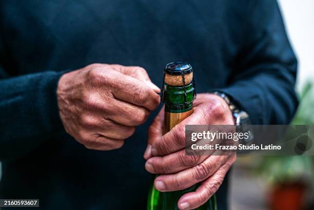 nahaufnahme eines mannes, der eine flasche champagner öffnet - sektkorken stock-fotos und bilder
