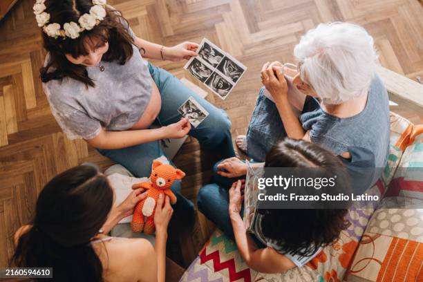 schwangere frau mit familie, die ultraschall des babys zu hause sucht - alte und junge lesbische frauen stock-fotos und bilder
