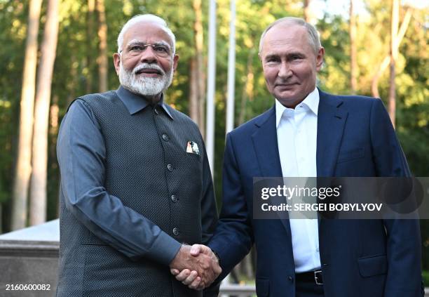 In this pool photograph distributed by the Russian state agency Sputnik, Russia's President Vladimir Putin welcomes Indian Prime Minister Narendra...