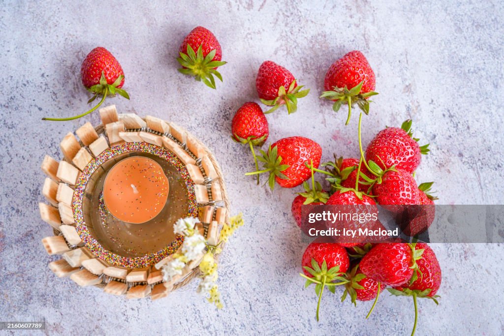Magnificent summer strawberry just after picking with a candle and a handmade tealight holder