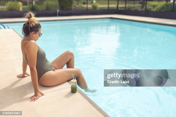 eine frau kühlt sich in einem schwimmbad ab und trinkt ein gesundes detox-getränk - stoffwechsel entgiftung stock-fotos und bilder