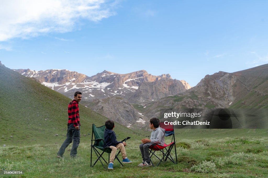 Little brothers and their father sitting and chatting with the view of Bolkar Mountains in Niğde Meydan Plateau