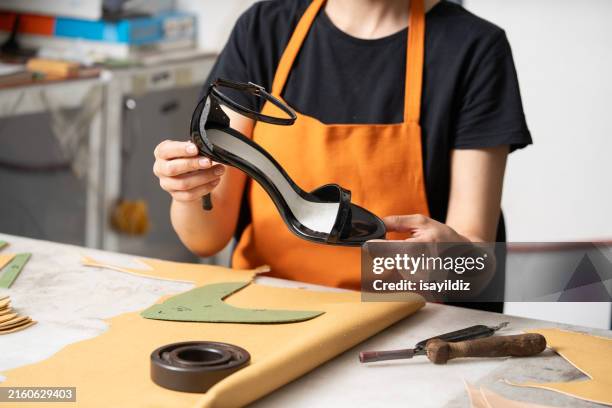 young woman in orange apron at workbench in shoe workshop - trestle stock pictures, royalty-free photos & images