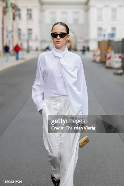 Berna Bilbey wears golden mini bag Prada, sunglasses Versace, white satin trousers Source Unknown, white shirt Source Unknown, black pointed kitten...