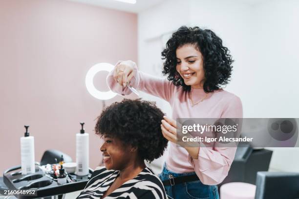parrucchiere che si prende cura dei capelli di un cliente - black hair stylist foto e immagini stock