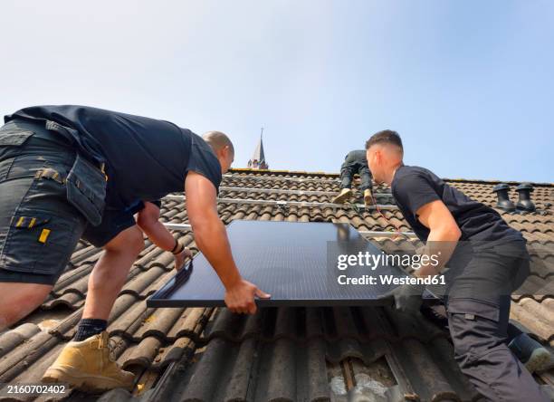 engineers installing solar panels on rooftop under sky - zonnepanelen stockfoto's en -beelden