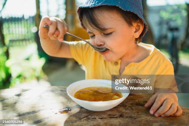 cute boy eating soup in back yard - scodella per zuppa foto e immagini stock