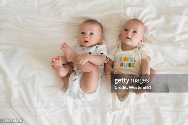 cute twin brothers lying on bed at home - identical twin stock pictures, royalty-free photos & images