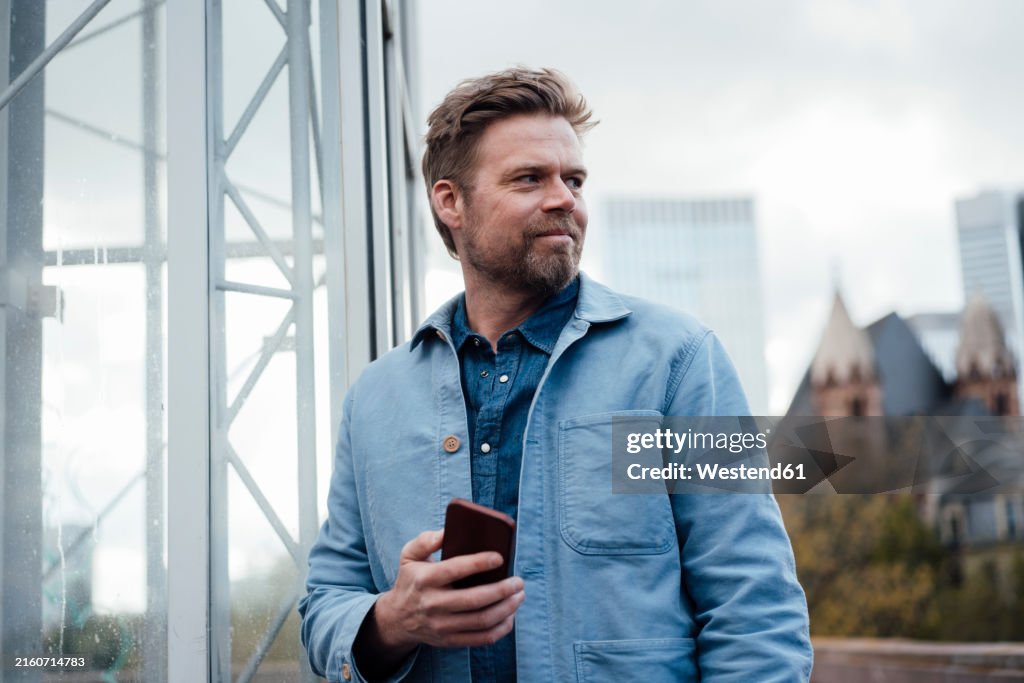 Smiling mature businessman holding mobile phone