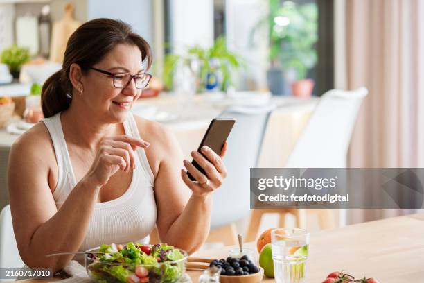 woman enjoying healthy vegetables meal and using phone - afvallen stockfoto's en -beelden