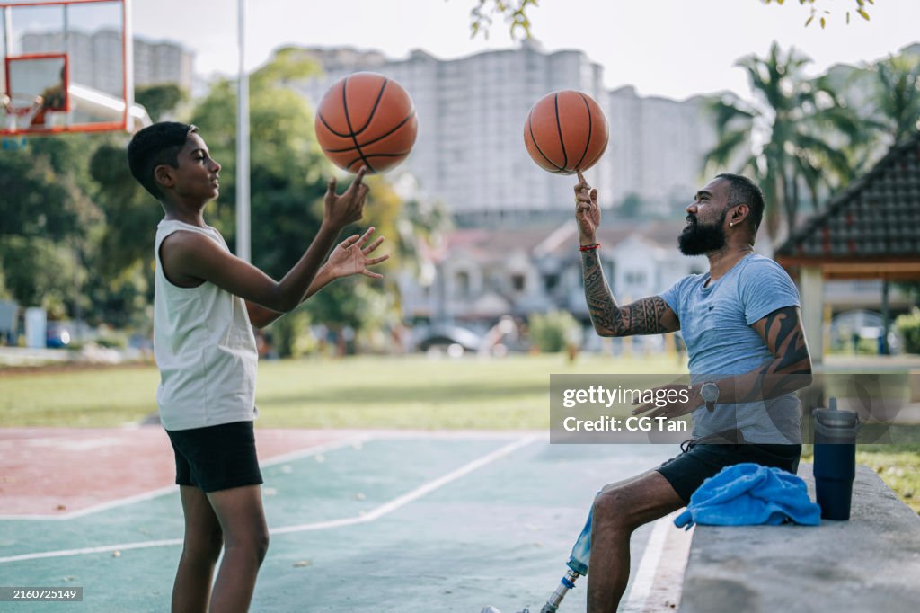 Asian indian father with amputee leg bonding with son playing basketball weekend activitiy