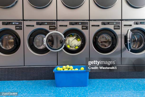 balls and sheet inside of washing machine near basket at laundromat - tennis machine stock pictures, royalty-free photos & images