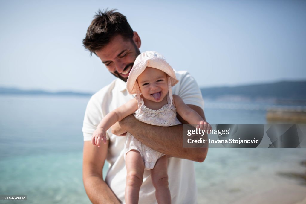 Little baby having fun with dad on the beach