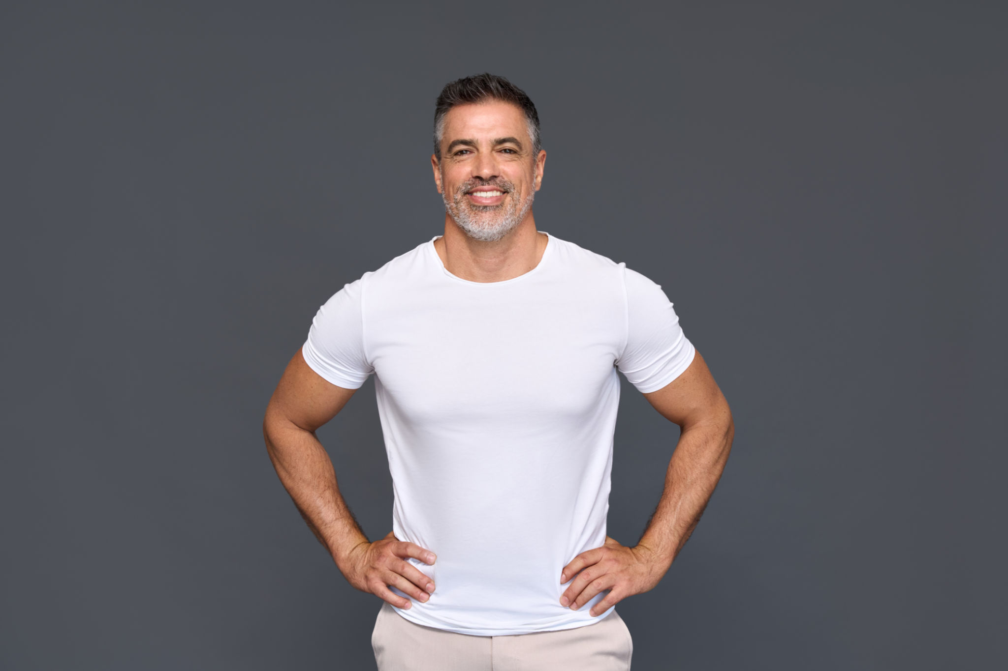 Happy fit sporty mature older man wearing white t-shirt isolated on background. Happy fit sporty mature older man wearing white t-shirt isolated on background.