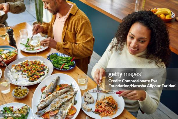 high angle view of extended family eating dinner together - serving dish stock pictures, royalty-free photos & images