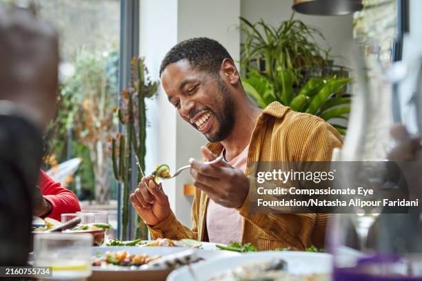 cheerful black man having lunch with family - fork stock pictures, royalty-free photos & images