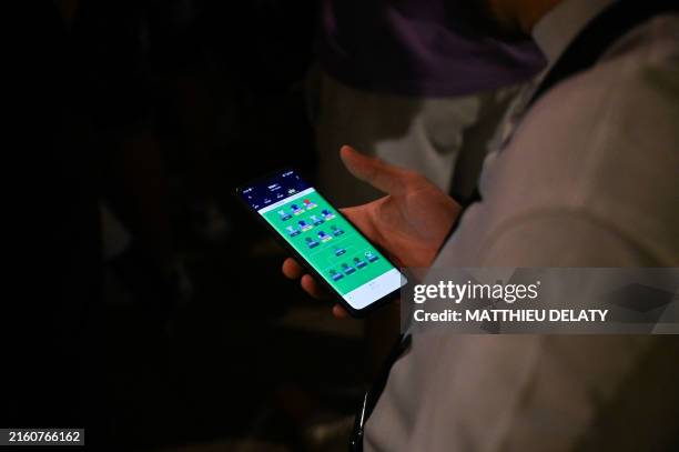 Fan of the French soccer team watches an online sports betting app during the live broadcast of the Euro 2024 semi final, Spain vs France, on the...
