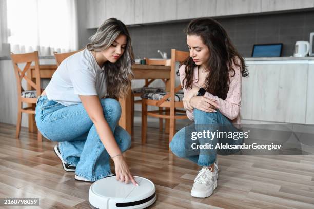compañeras de cuarto configurando su aspiradora robótica inteligente - aspiradora-artículo-de-limpieza fotografías e imágenes de stock