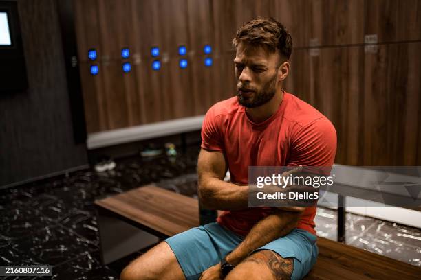 tired athletic man having arm injury in locker room. - locker room stock pictures, royalty-free photos & images
