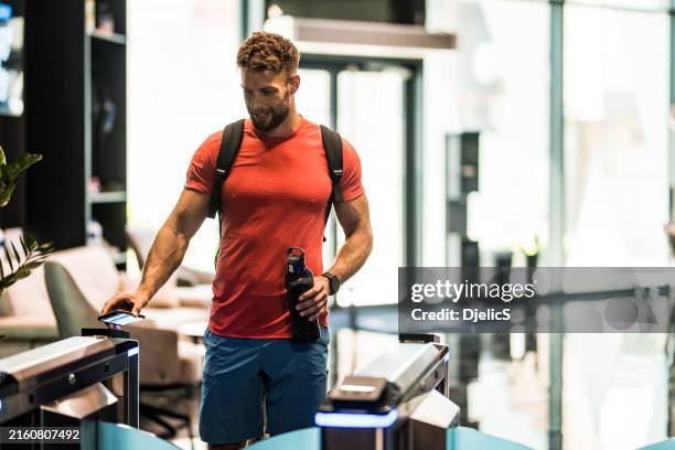 junger männlicher sportler betritt ein modernes fitnessstudio und scannt sein telefon. - gehen sportdisziplin stock-fotos und bilder