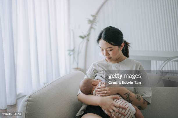 asiatico cinese giovane madre che allatta al seno bambina a casa - allattamento foto e immagini stock