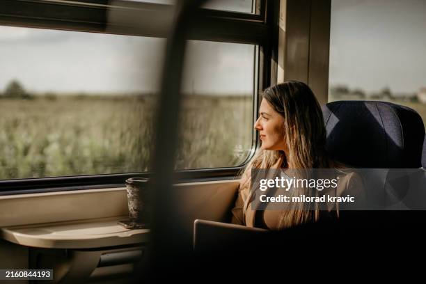 young woman travels by train, using lap top and looking out the window - looking through window stock pictures, royalty-free photos & images